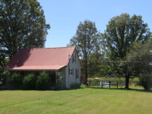 A red roof house in the middle of a field.